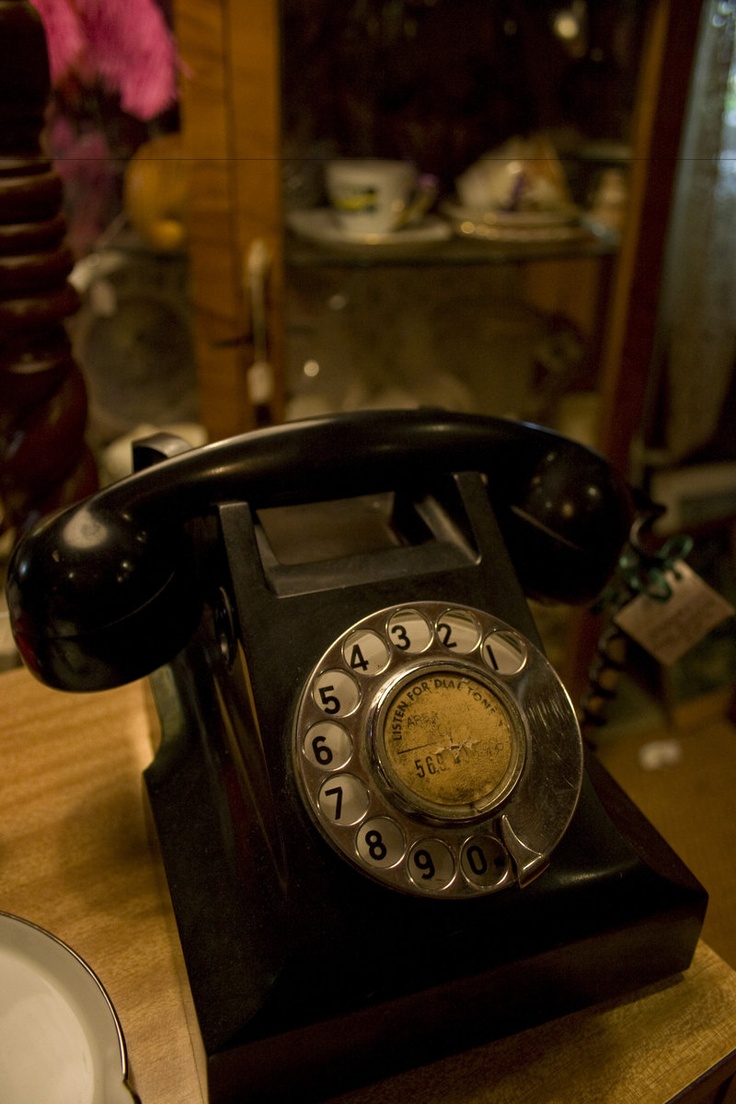 an old fashioned phone sitting on top of a wooden table