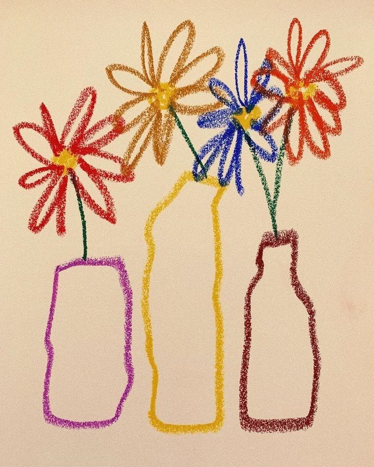 three colored crayon flowers in a vase with a bottle on the table next to it