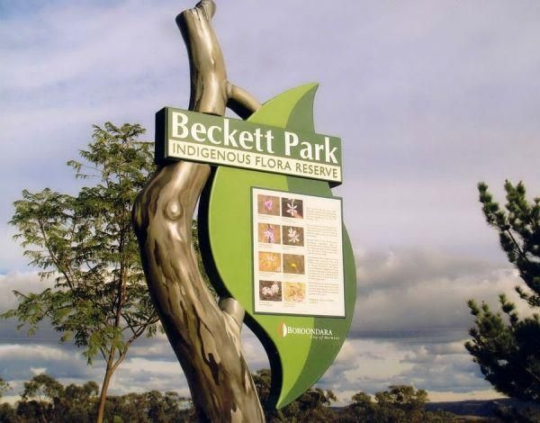 a sign for the backett park in front of some trees and bushes on a cloudy day