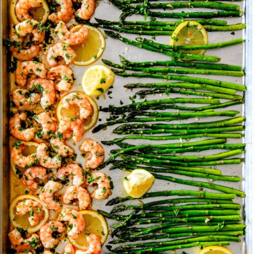 asparagus, lemons and shrimp on a baking sheet