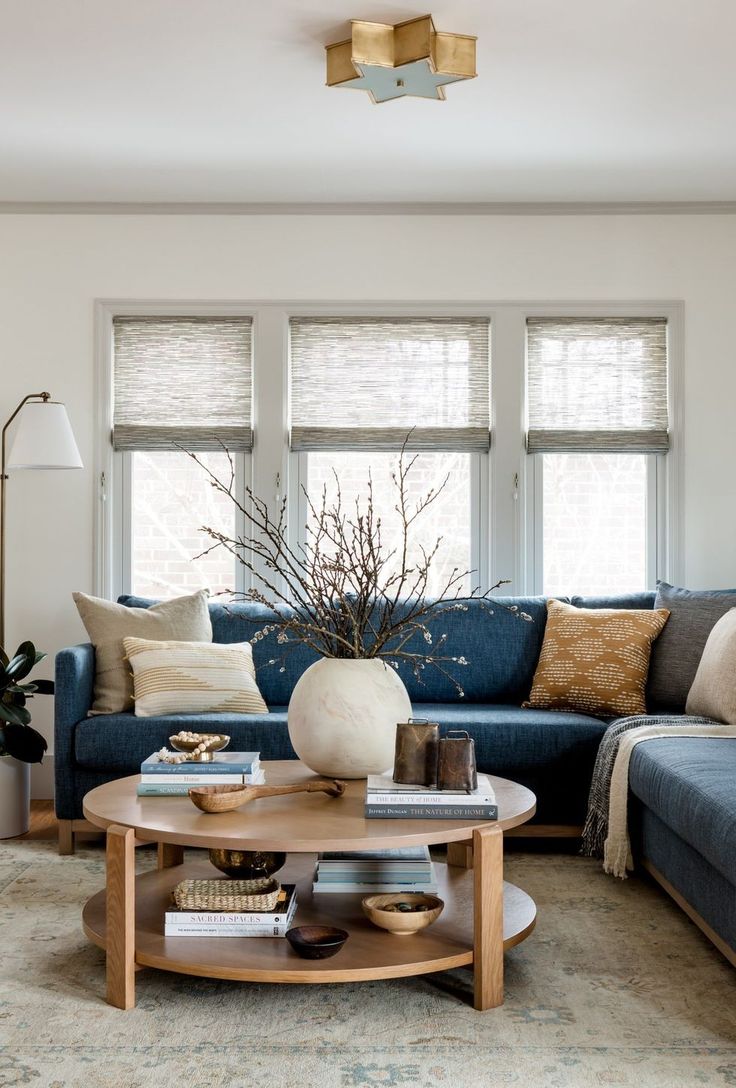 a living room with a blue couch and coffee table in front of two large windows