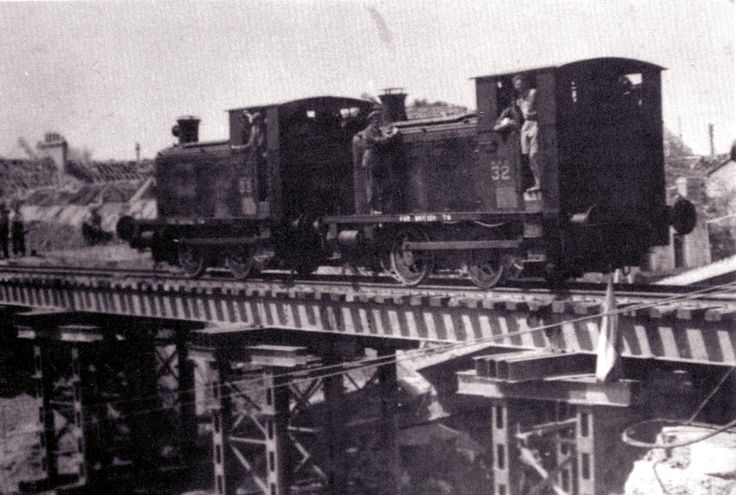 black and white photograph of an old train going over a bridge