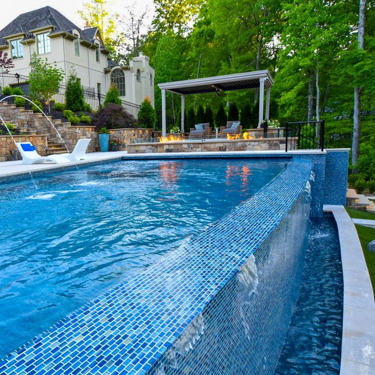 an outdoor swimming pool surrounded by landscaping