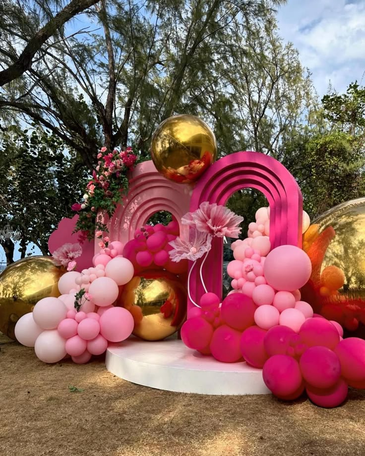 balloons and decorations are arranged on the ground in front of trees, bushes and flowers