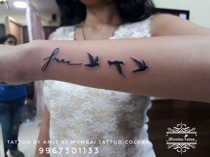 a woman with a tattoo on her arm that has birds flying in the sky above it