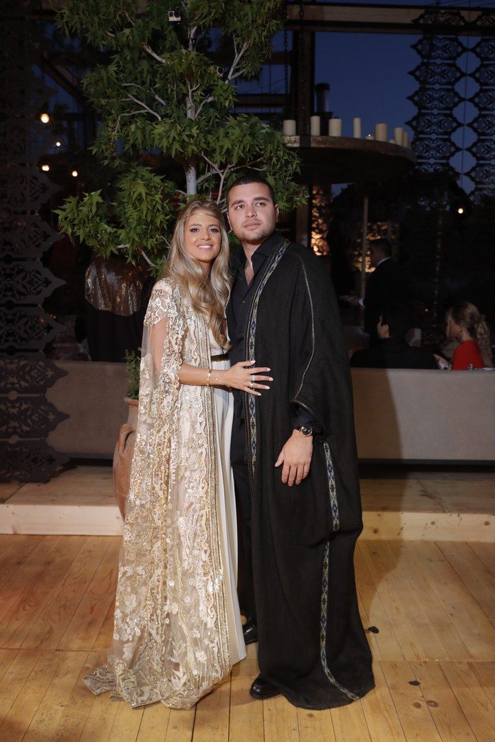 a man and woman standing next to each other on a wooden floor in front of a tree