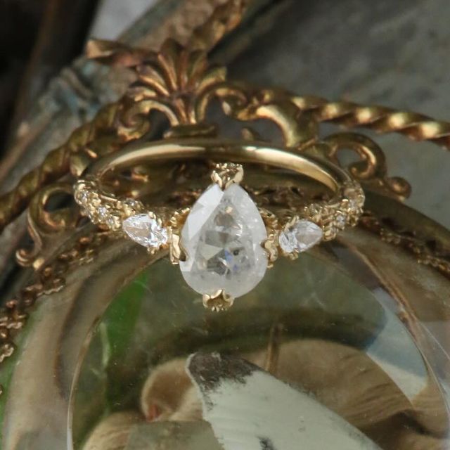 a close up view of a ring with an oval shaped diamond in the center and two smaller round diamonds on each side