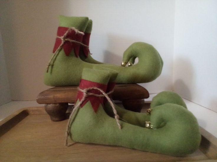 two green christmas stockings sitting on top of a wooden sleigh with red ribbon