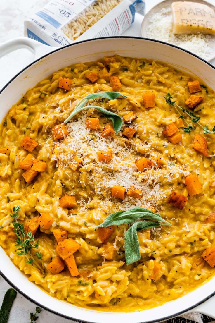 a white bowl filled with pasta and carrots on top of a table next to bread