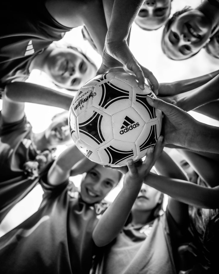 a group of people holding a soccer ball in the middle of each other's hands