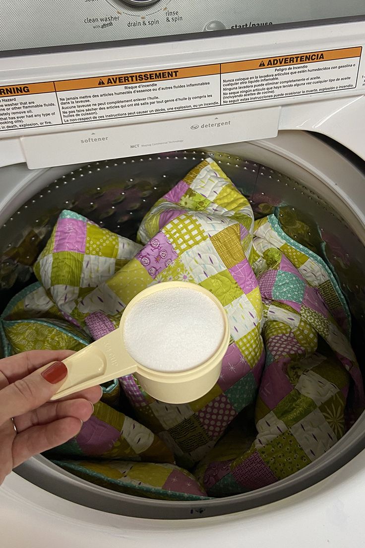 a person is holding a spoon in front of a washing machine filled with cloths