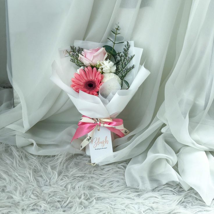 a bouquet of flowers sitting on top of a white furnishing next to a tag