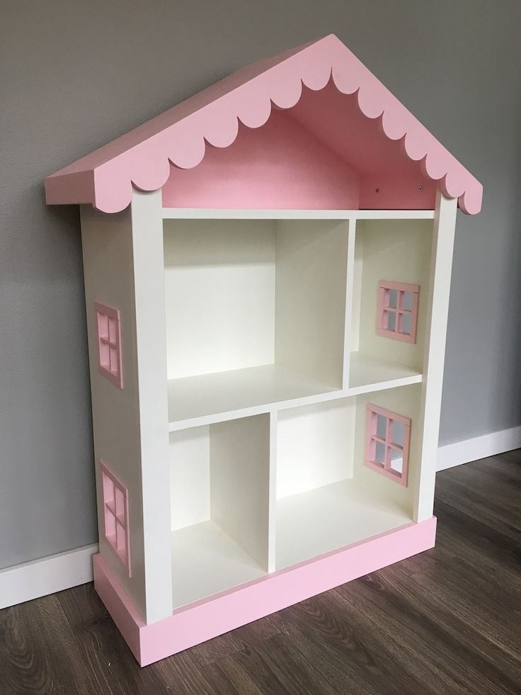 a pink and white doll house with windows on the top shelf is sitting in front of a gray wall