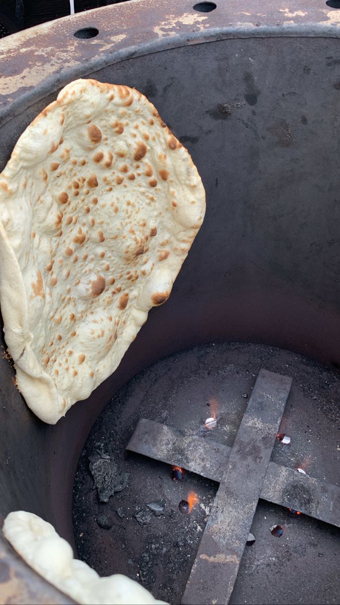 a pita bread sitting on top of a metal pan next to an iron cross