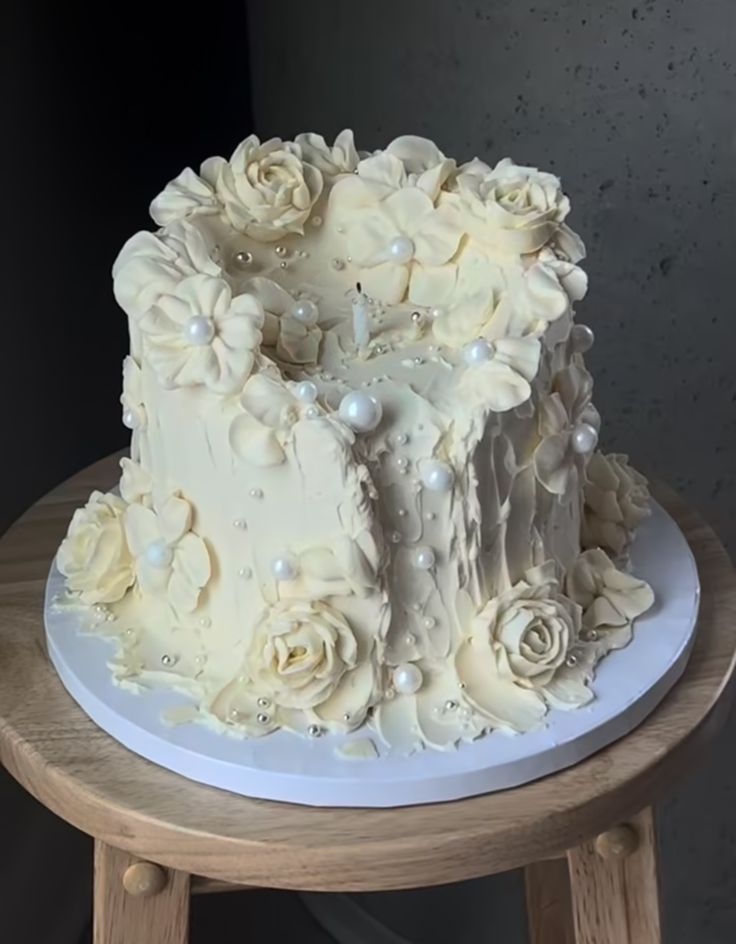 a white wedding cake with flowers and pearls on the top is sitting on a wooden table