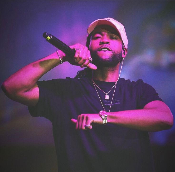 a man holding a microphone in his right hand and wearing a hat on top of his head