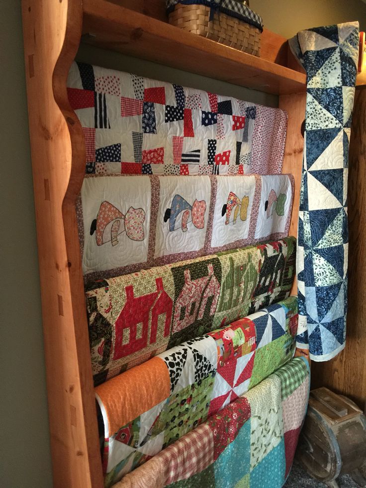 quilts are hanging on the wall next to each other in a room with wood shelving