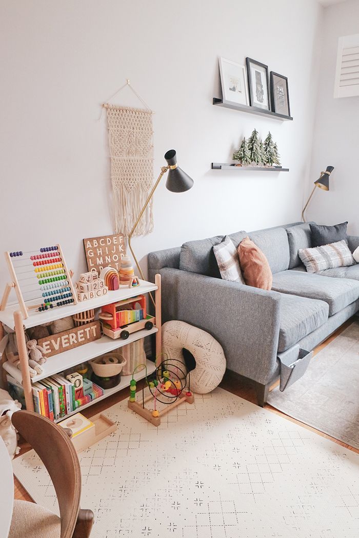 a living room with a gray couch and bookshelf on the wall next to it