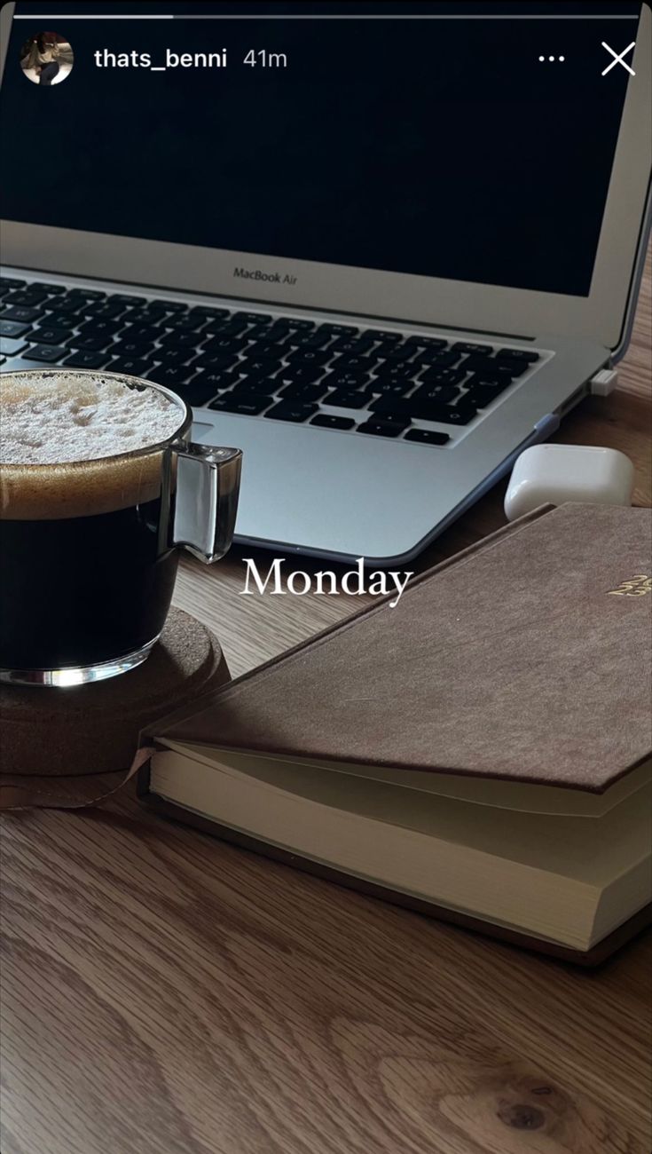 a laptop computer sitting on top of a wooden desk next to a cup of coffee