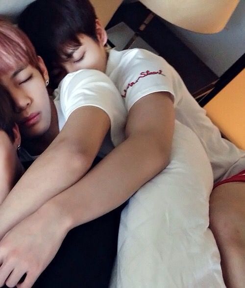 two people are sleeping on a bed with their arms around each other and one person is holding the other