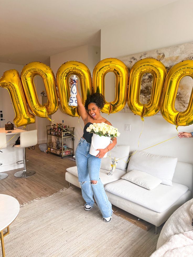 a woman standing in front of balloons that spell out the word boo on a wall