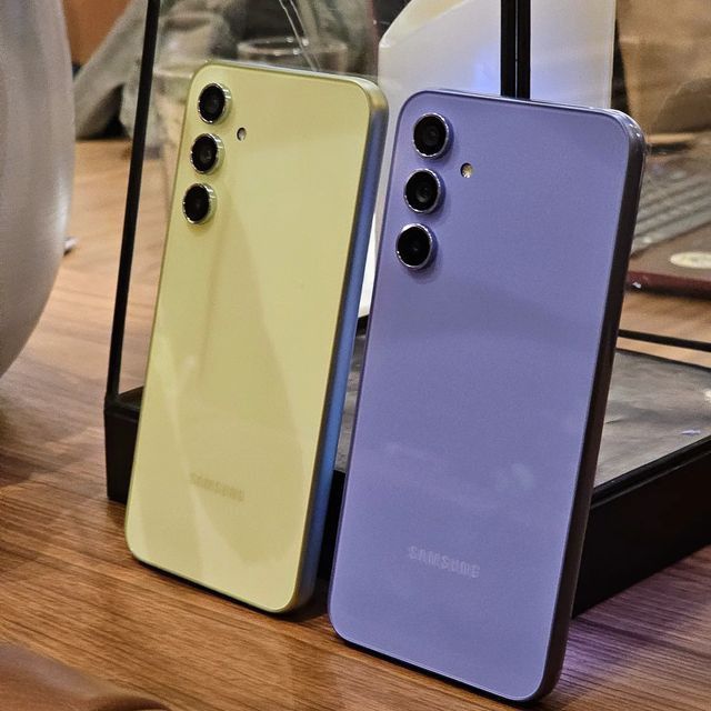 two different colored cell phones sitting next to each other on top of a wooden table