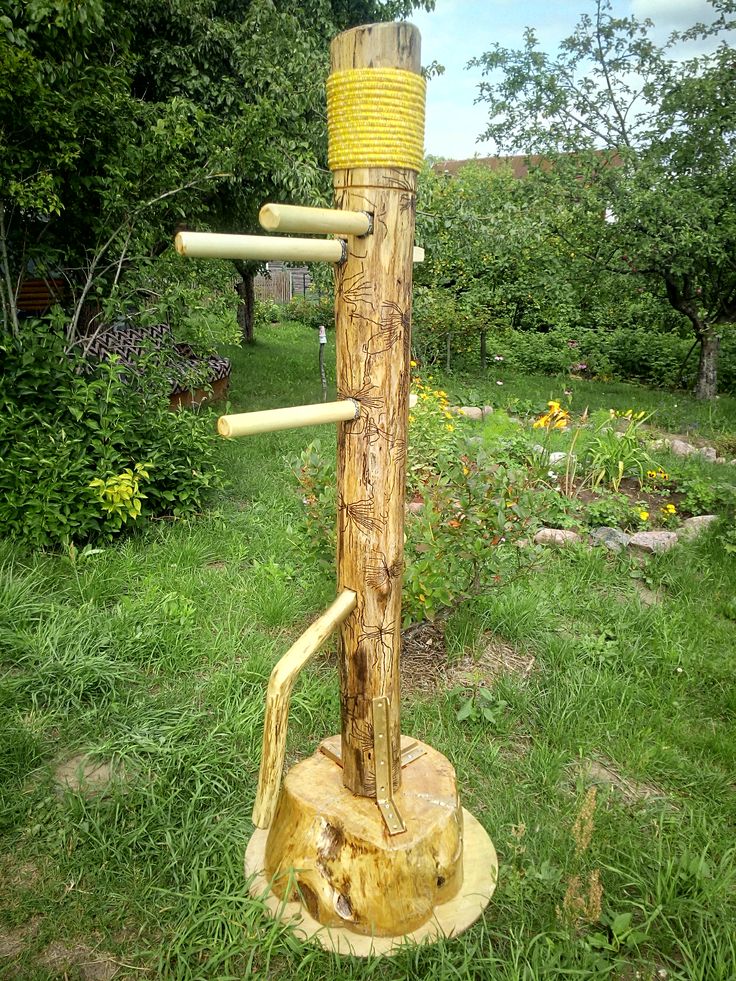 a wooden pole with several ropes attached to it in the grass next to some trees