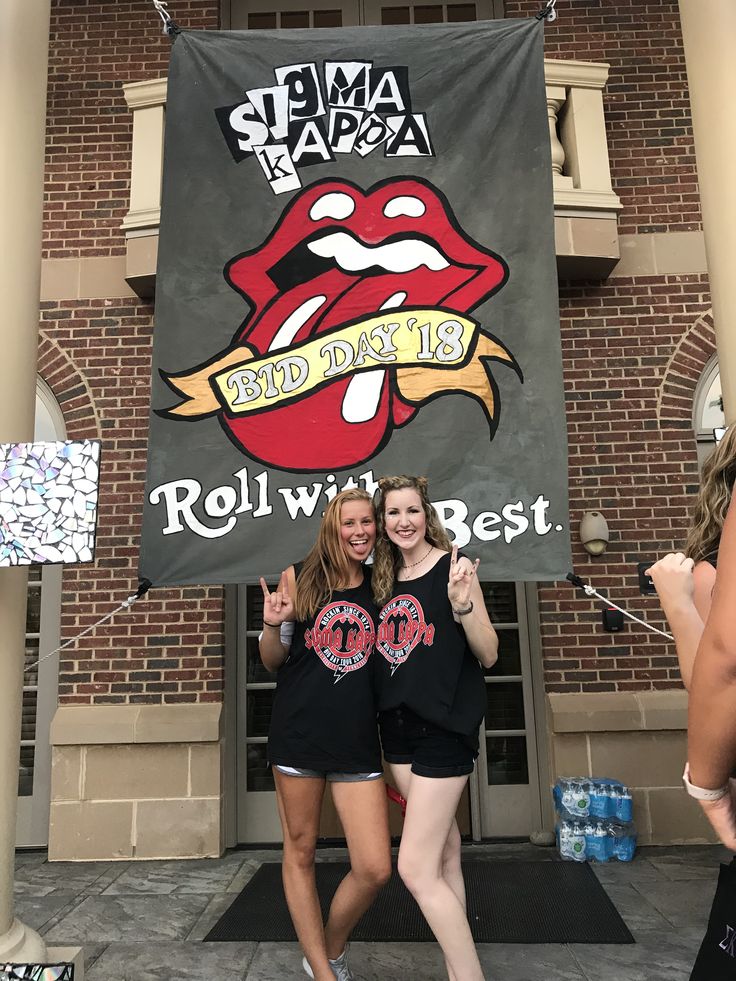 two young women standing in front of a building holding up a sign that says roll with best