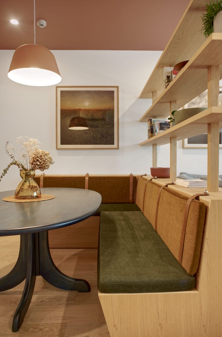 a table and bench in a room with wood flooring, built - in bookshelves and open shelving