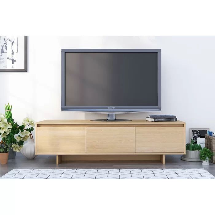 a flat screen tv sitting on top of a wooden cabinet in front of a white wall