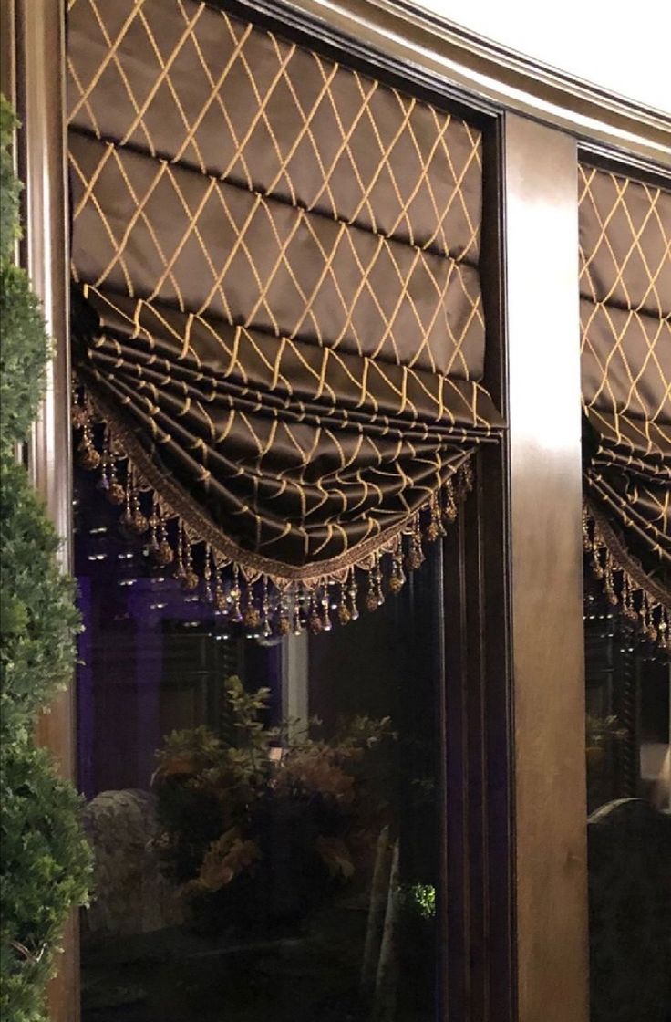 a window covered in brown curtains next to a potted plant