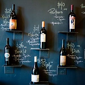 several bottles of wine are lined up on the wall in front of a chalkboard