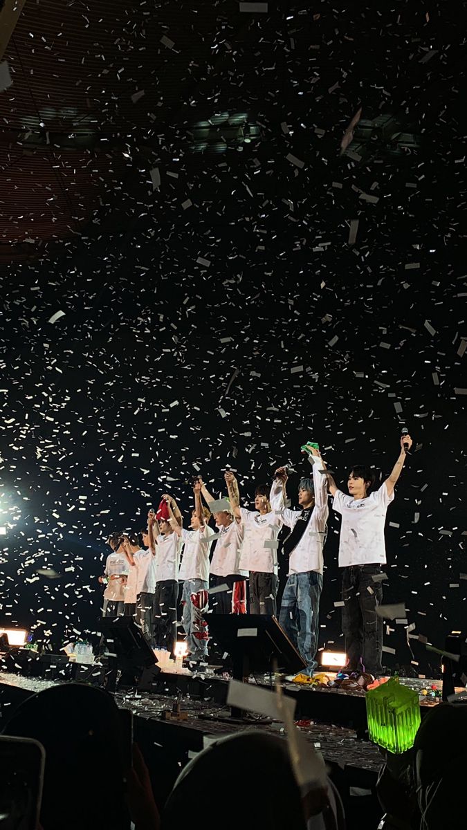 a group of people standing on top of a stage with confetti in the air