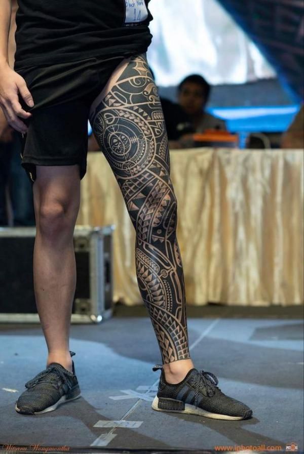 a man with tattoos on his legs and leggings is standing in front of a stage