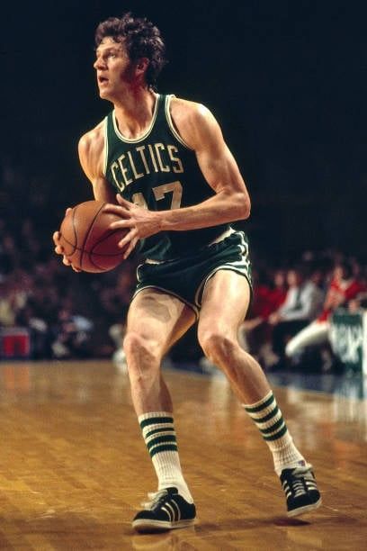 a basketball player dribbles the ball during a game with an audience in the background