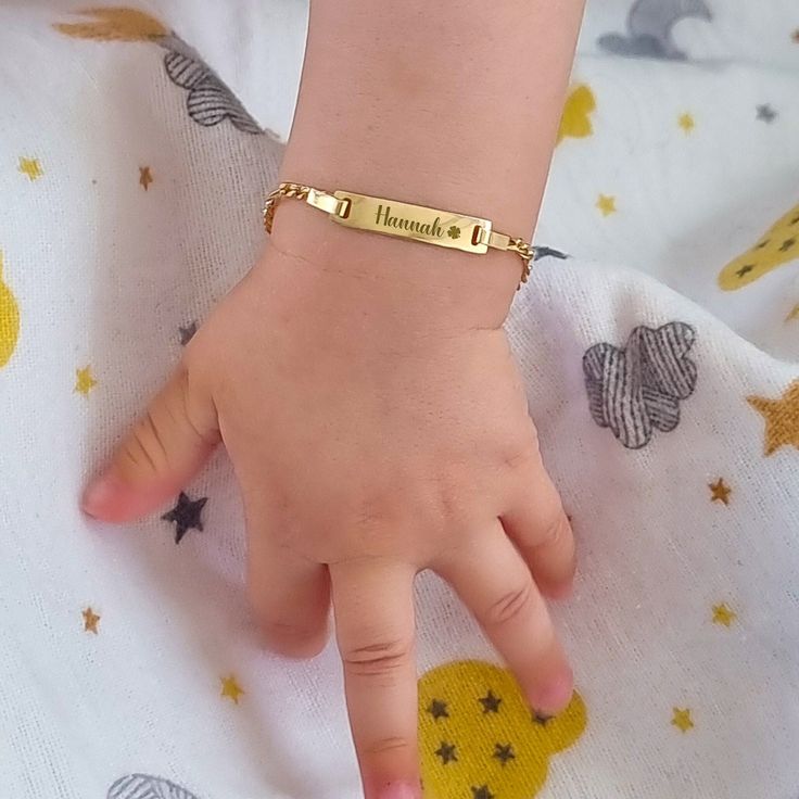 a child's hand with a gold bracelet on it