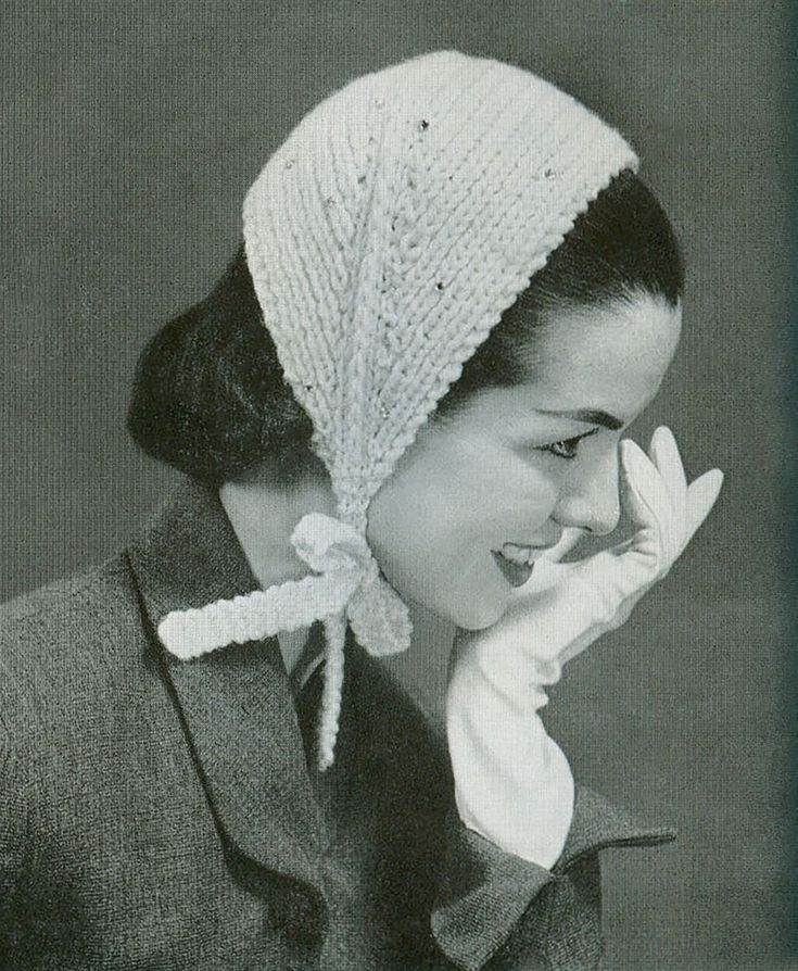 an old photo of a woman wearing a knitted hat and holding her hand up to her face