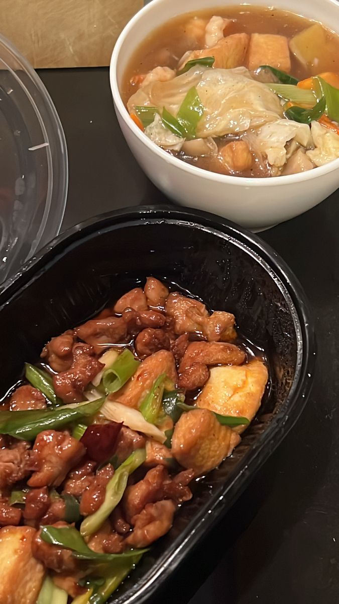 a bowl of soup with meat and vegetables in it next to a container of rice