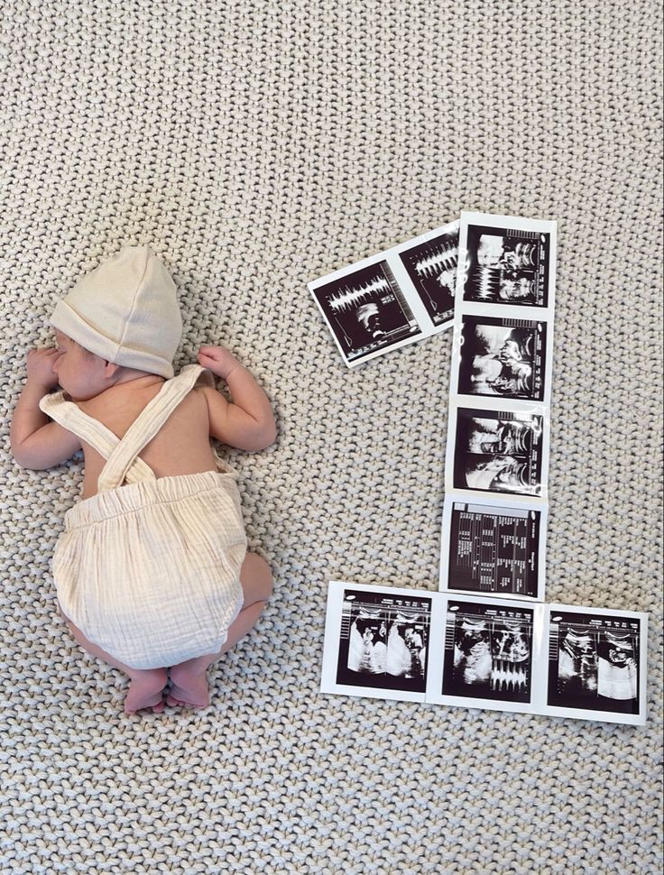 a baby is laying on the floor with some pictures and a bag next to it