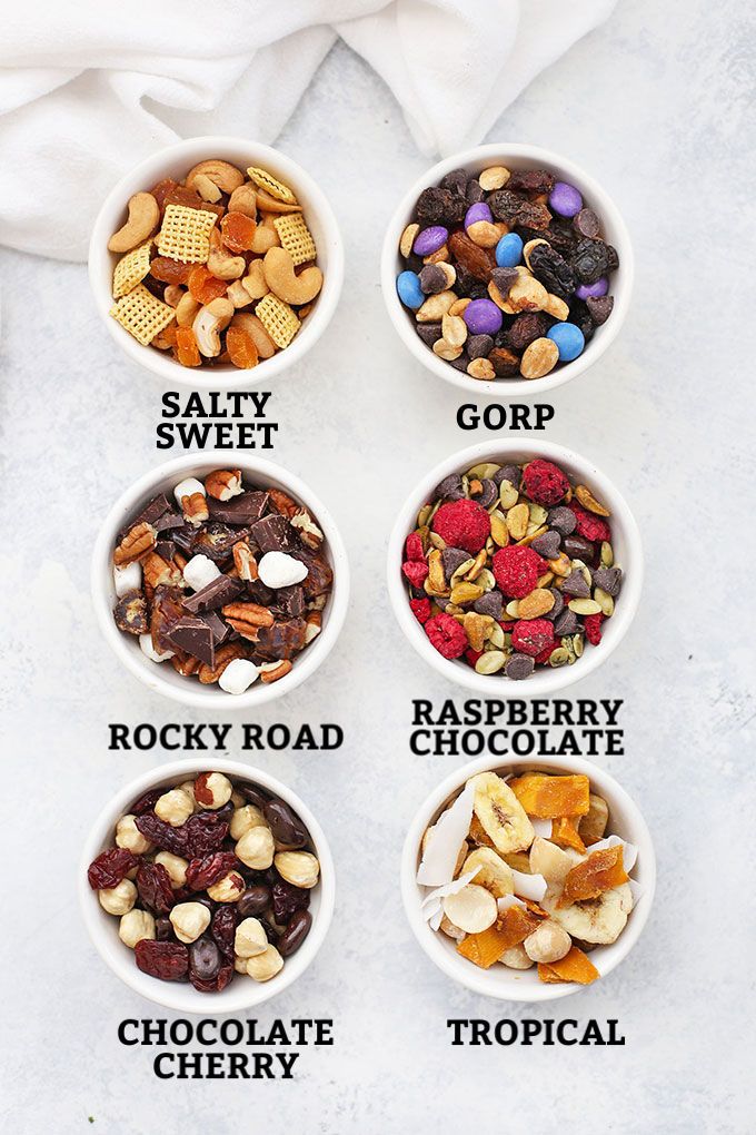 four bowls filled with different types of nuts and chocolates on top of a white surface