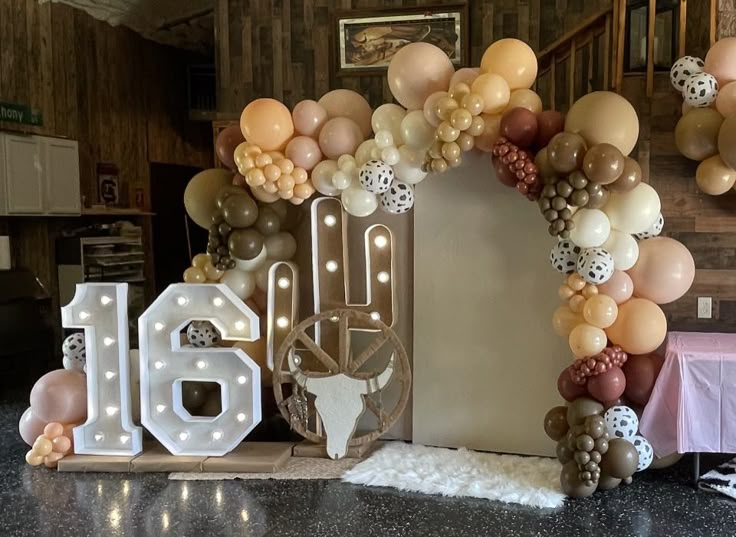 a table topped with balloons and letters that spell out the word 16 in front of a wall