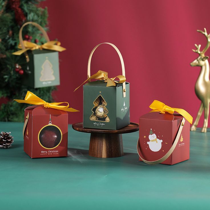 three christmas gift boxes sitting on top of a table next to a small deer figurine