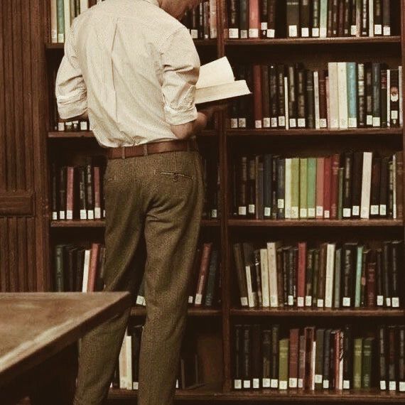 a man standing in front of a bookshelf with lots of books on it