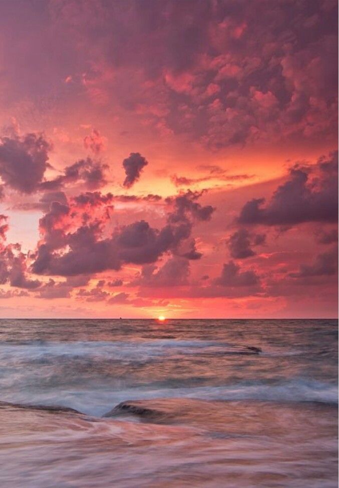 the sun is setting over the ocean with clouds