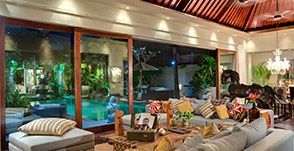 a living room filled with lots of furniture next to a large window covered in plants