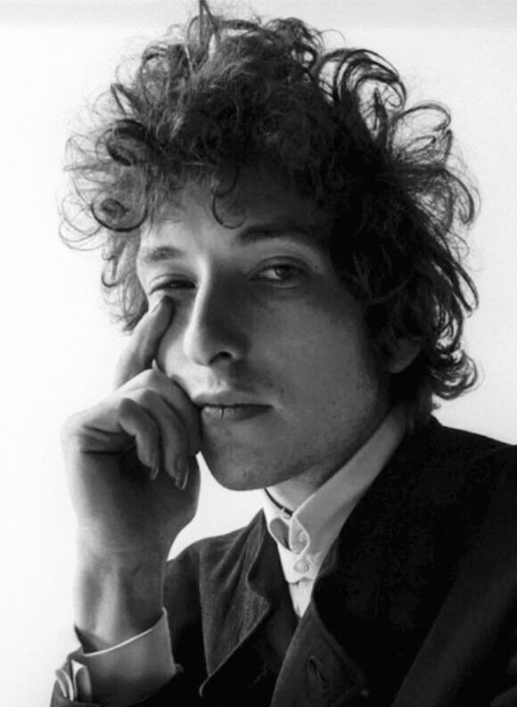 black and white photograph of a man with curly hair holding his hand to his face