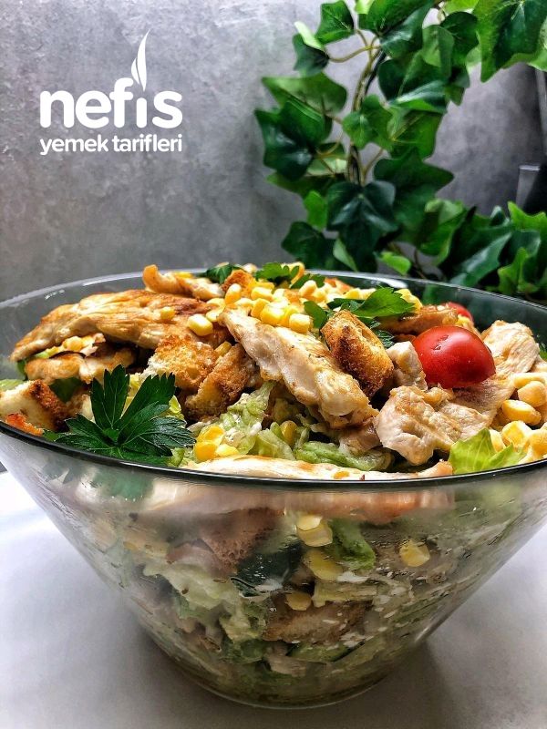 a salad with chicken, corn and tomatoes in a glass bowl