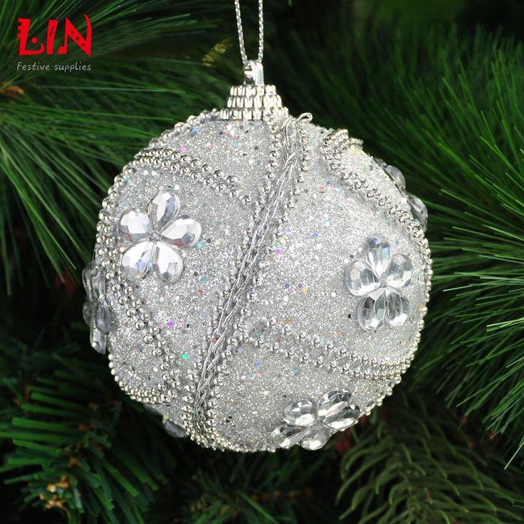 a christmas ornament hanging from a tree with snow flakes and crystals on it