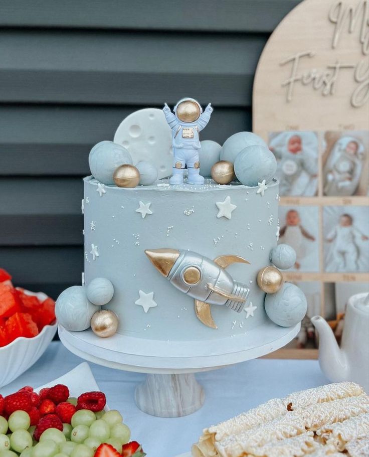 a blue cake with an astronaut on top and other desserts in the foreground