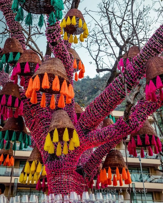 many different colored tassels hanging from a tree in front of a large building